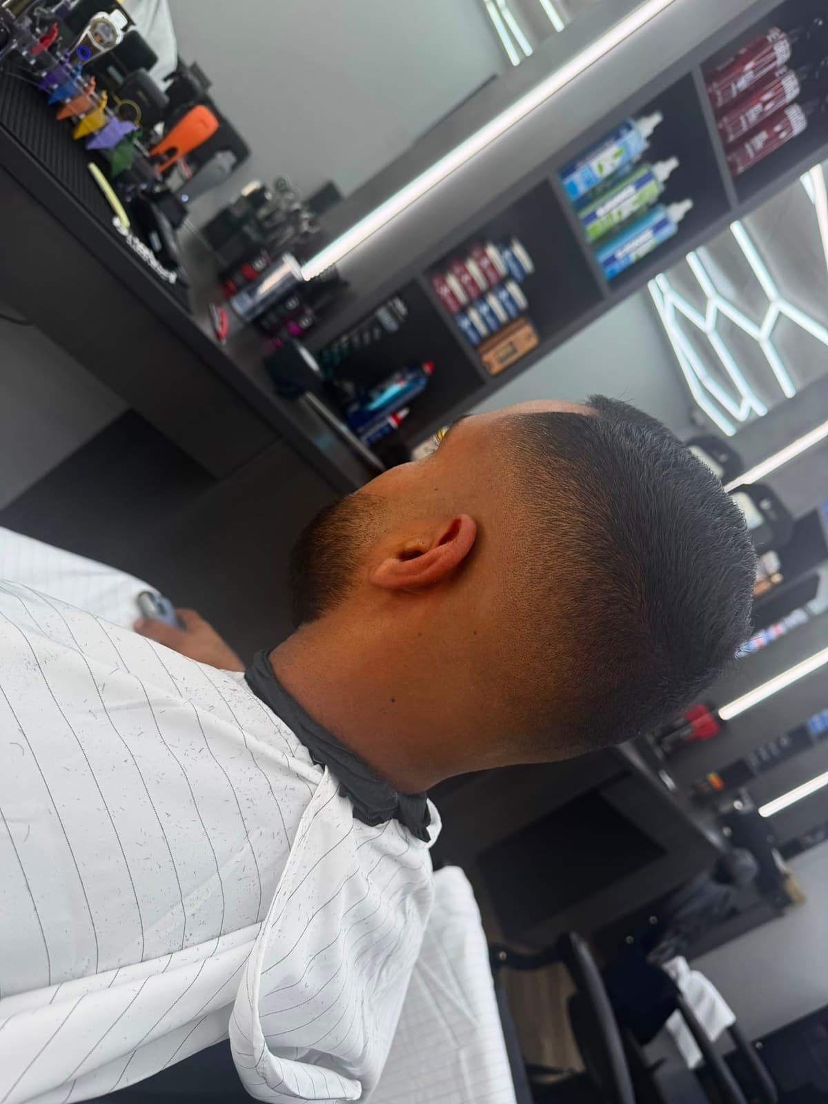 A tight fade freshly cut, station and product shelving in the background